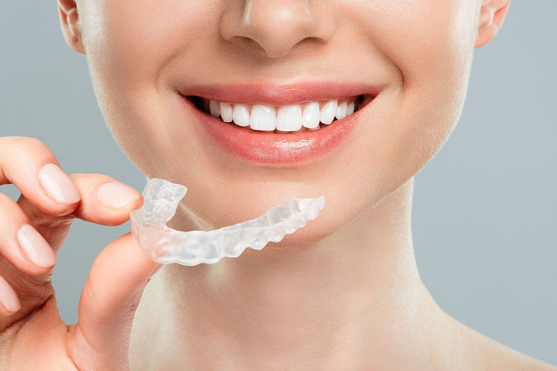 smiling woman holding Invisalign