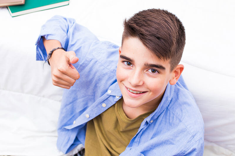top-down shot of a boy with braces giving a thumbs-up